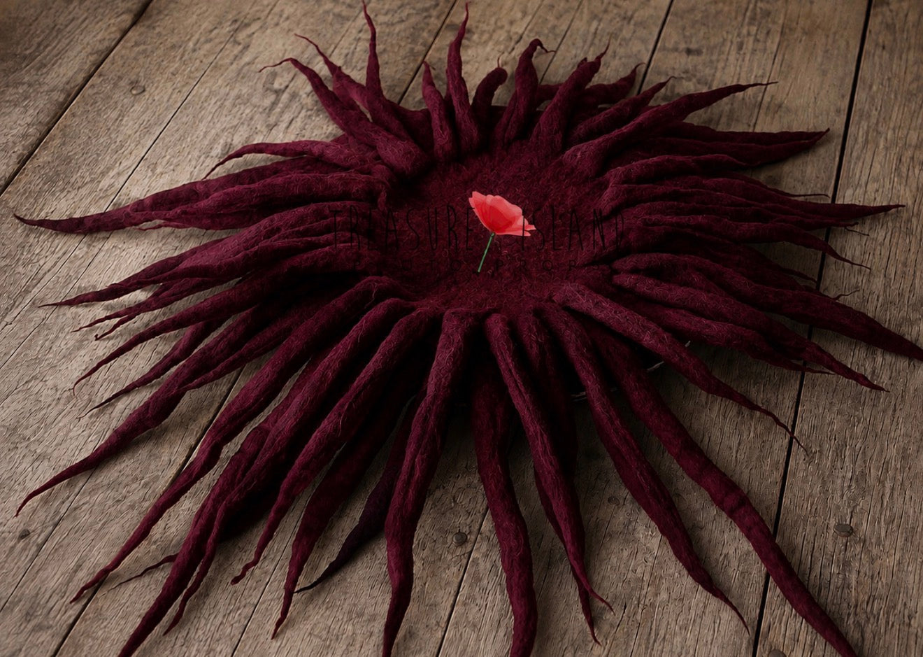 A large, dark burgundy dreadlock hairpiece displayed flat on a rustic wooden surface, featuring a small red rose pinned in the center.
