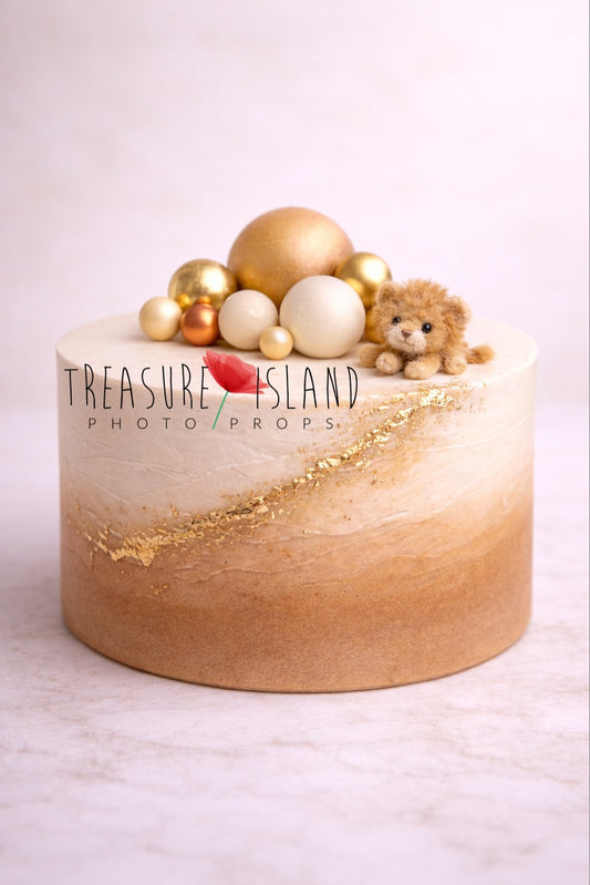 Styrofoam cake from the Safari Collection – Lion Cub Edition. Designed for cake smash photography with a soft ombre blend from caramel to warm ivory tones and a circular textured surface. Finished with subtle golden accents, decorative spheres and a miniature handcrafted needle-felted lion cub for an elegant safari styling.