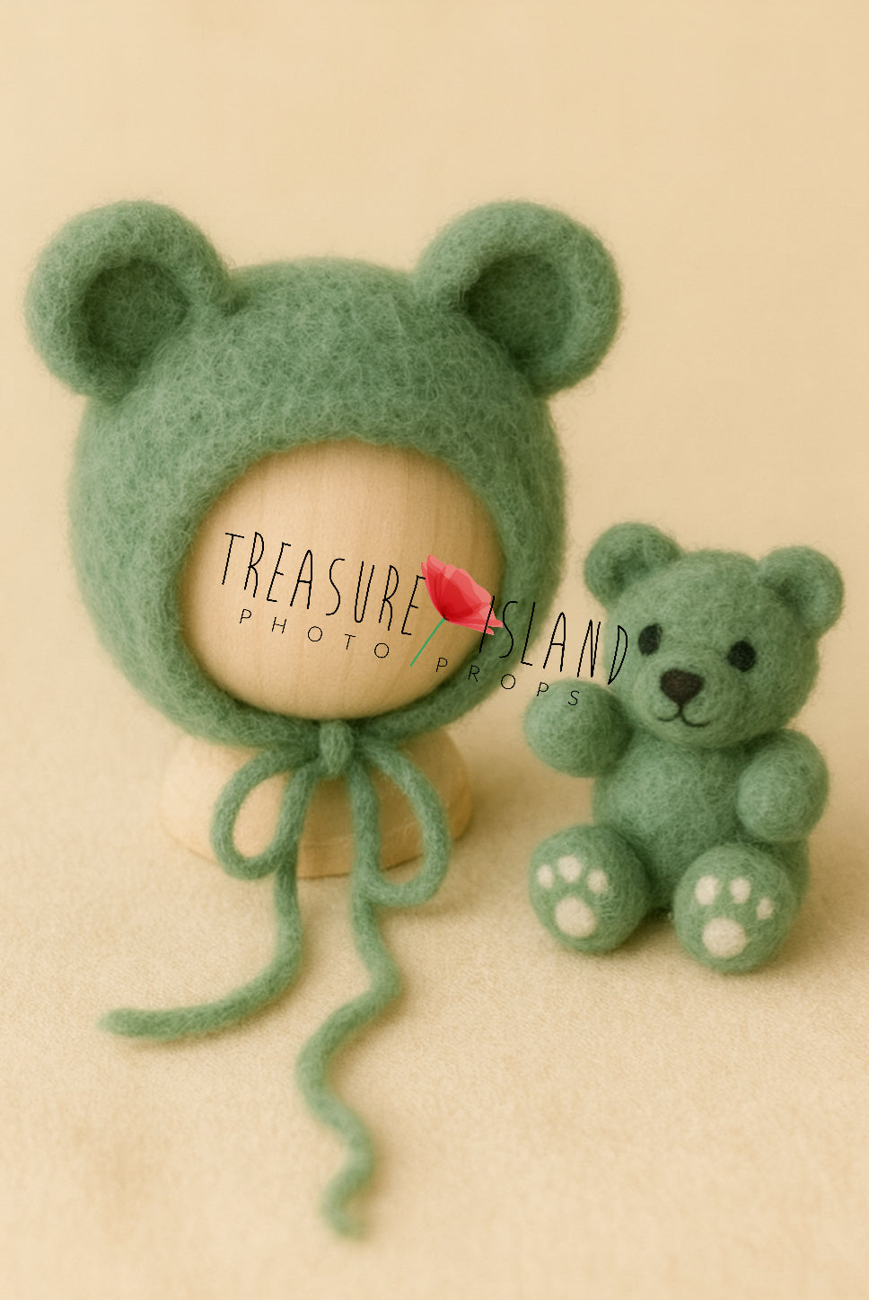 Green baby bonnet and toy bear on a beige background with 'Treasure Island Photo Props' branding.