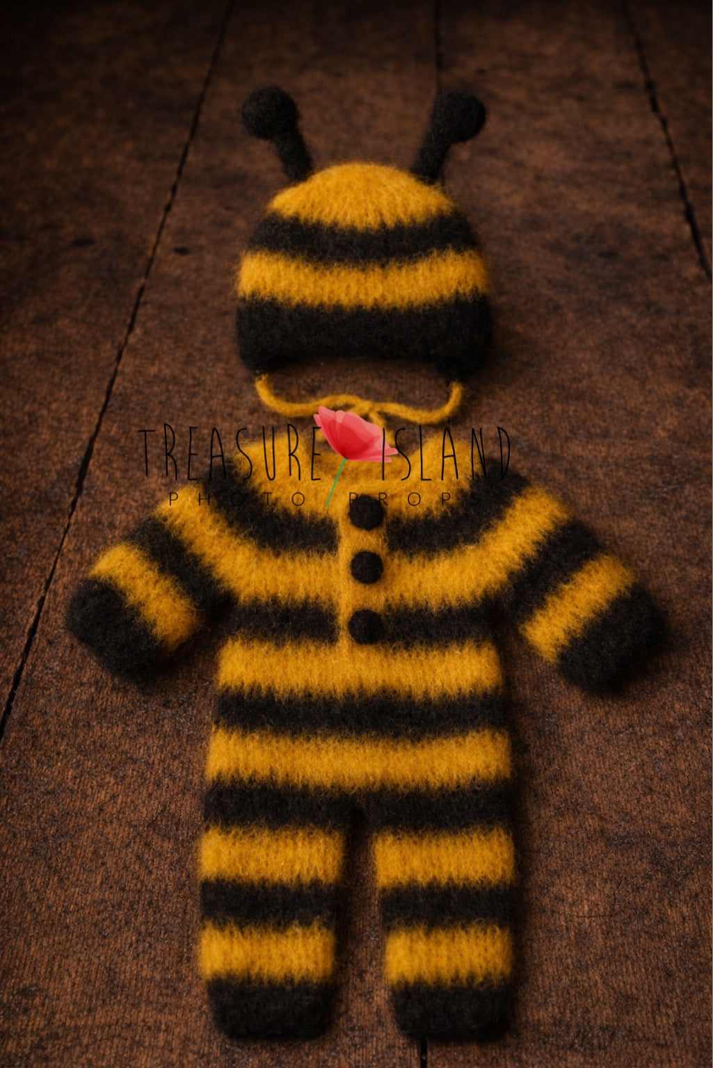 handmade newborn bee outfit set with striped knit romper and matching bonnet on rustic wooden floor
