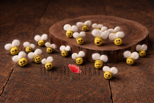 tiny handmade mini felt bees for newborn photography prop styled on rustic wooden floor with natural wood slice
