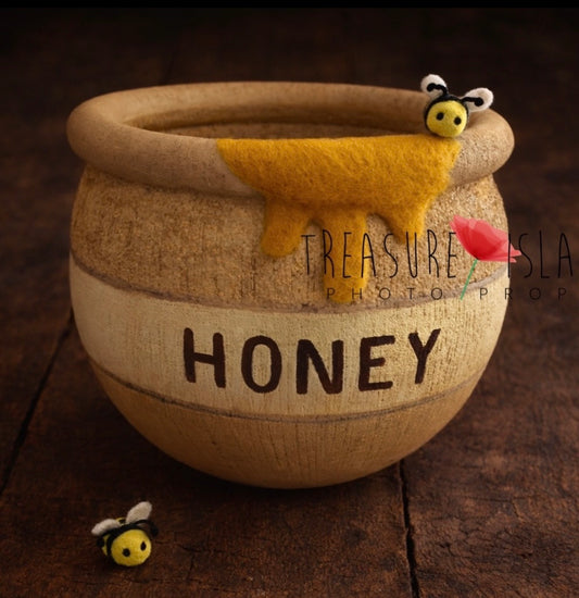 handmade honey pot newborn photography prop with felt bees on rustic wooden floor, natural wood texture and soft wool detail