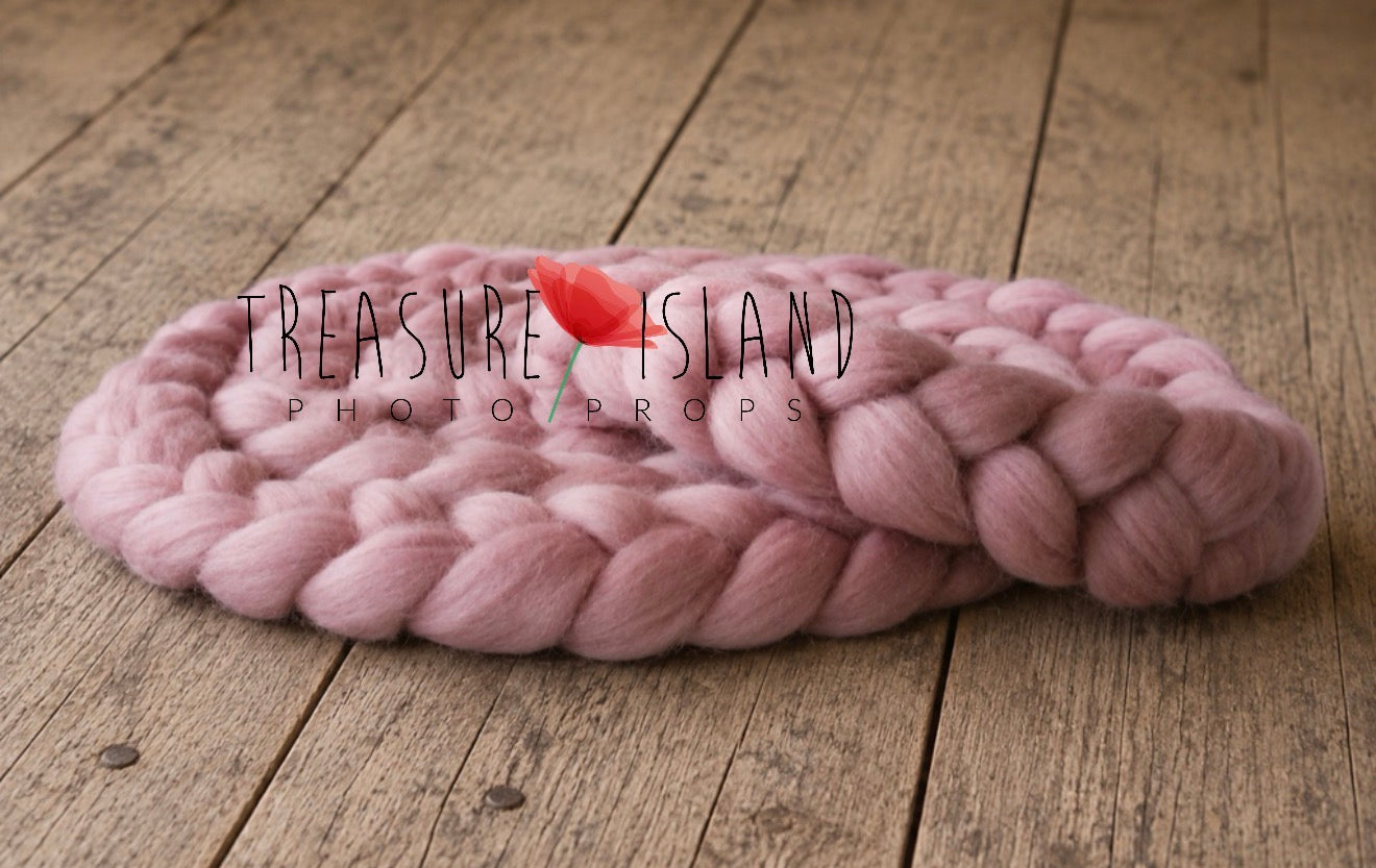 A chunky knit pink blanket or cushion with a small red tulip flower on top, placed on a rustic wooden surface. A watermark reading 'Treasure Island Photo Props' is overlaid across the center.