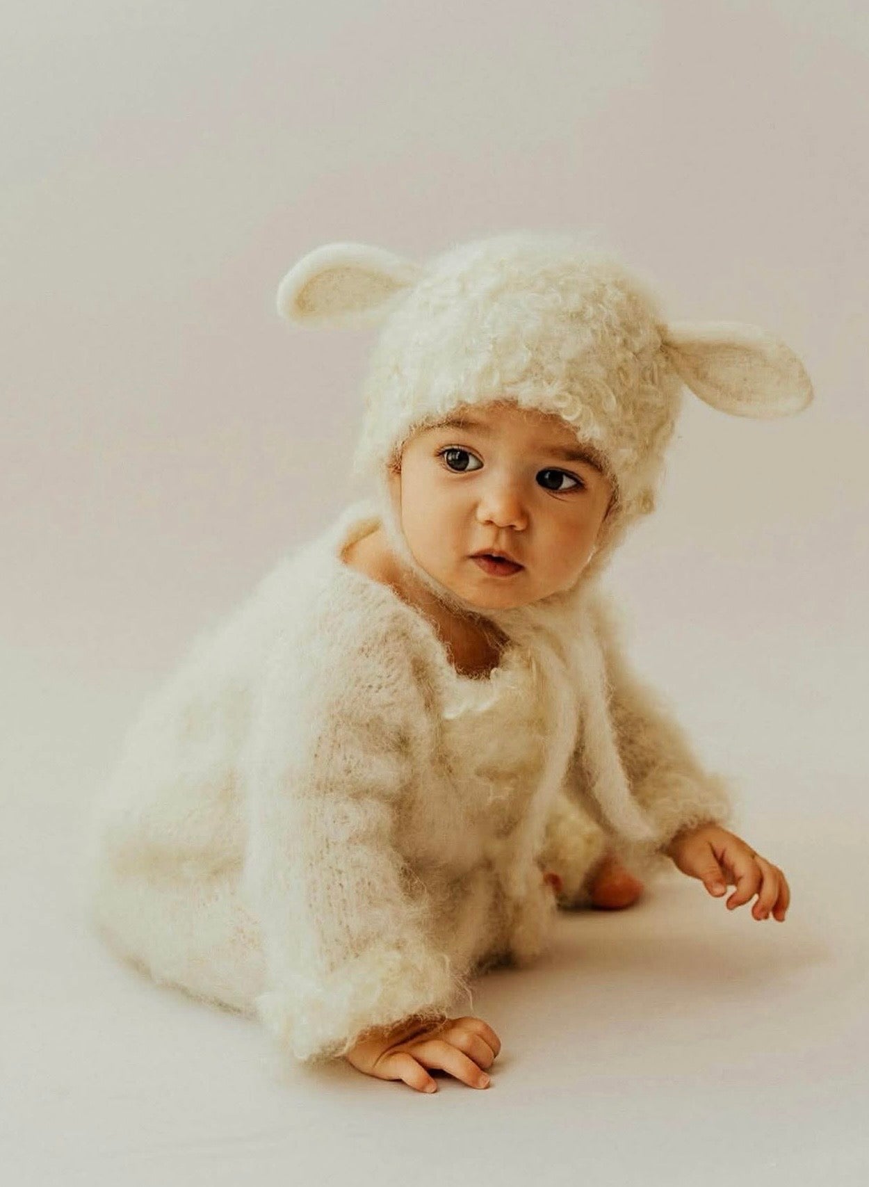 Curly lamb romper and bonnet outfit styled in a newborn photography session