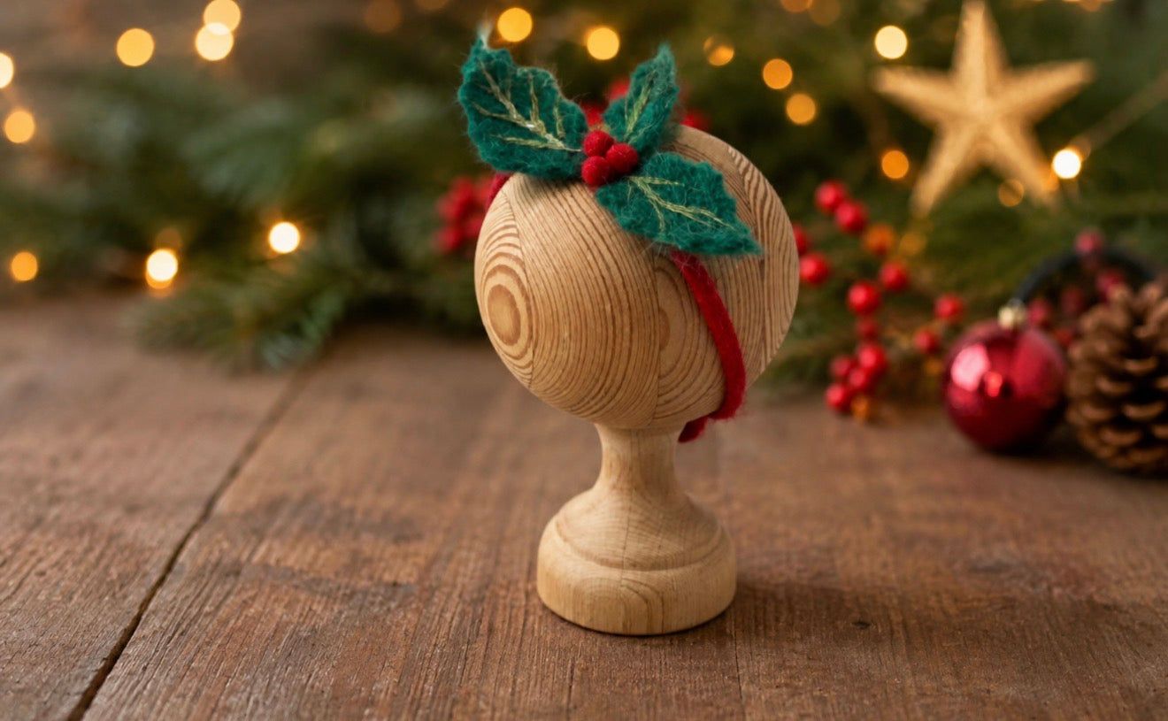 Hand-felted Christmas holly headband with green leaves and red berries styled for newborn holiday photography