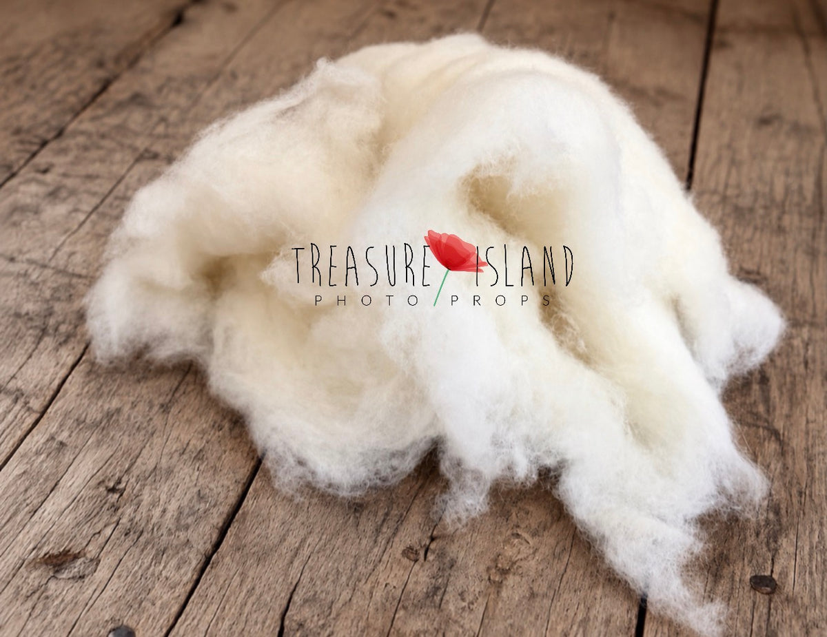 Extra fluffy ivory white wool cloud photography prop with soft airy fibres and irregular edges, arranged on a rustic wooden floor
