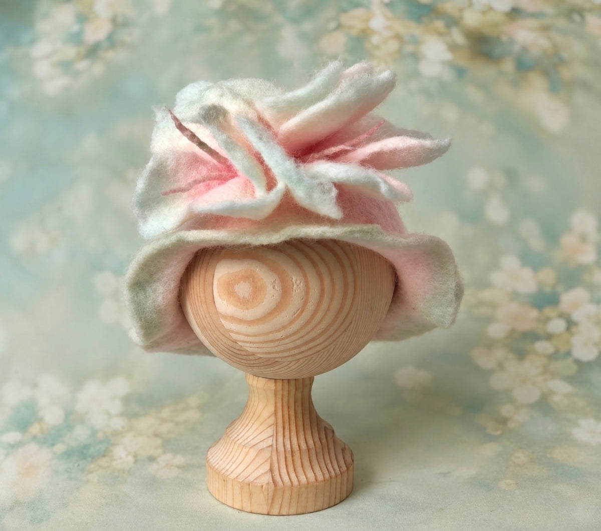 Top view of handmade felted flower petal hat showing sculptural wool petals, delicate pink stamens and soft colour transitions