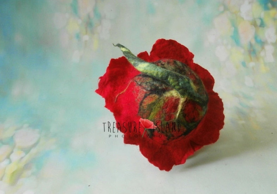 Top view of hand-felted red poppy bonnet showing layered petals and botanical green detailing