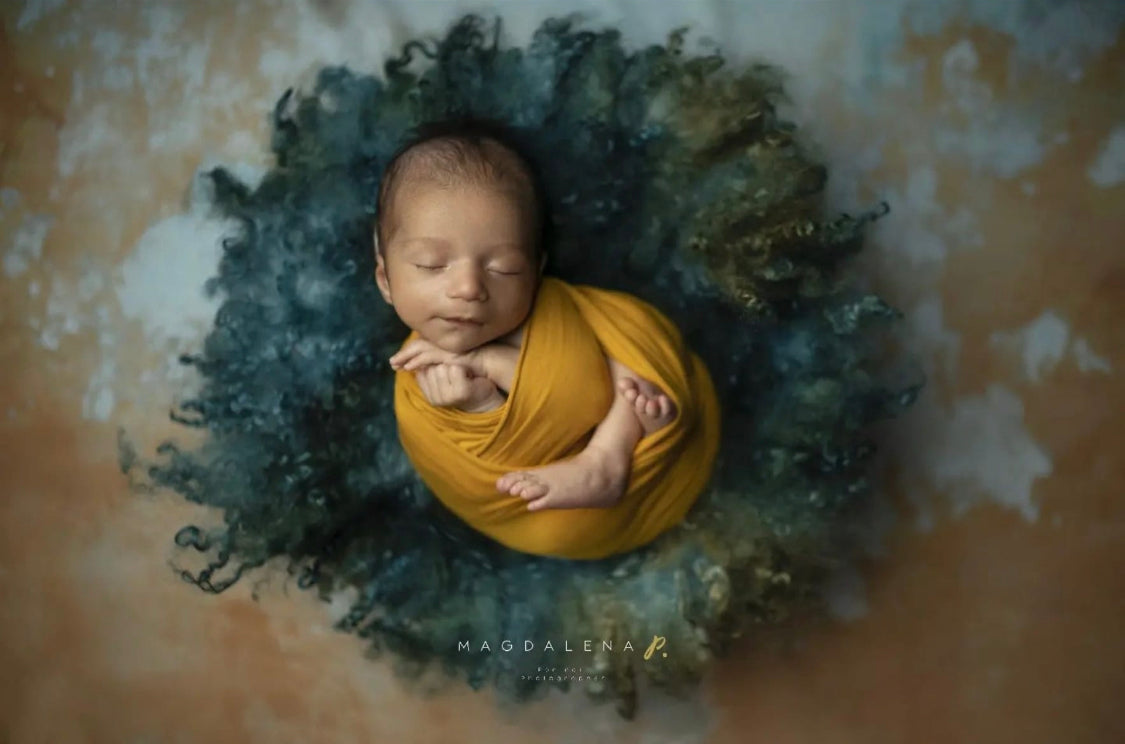 Forest green and teal curly wool blanket used as a textured layer for newborn photography