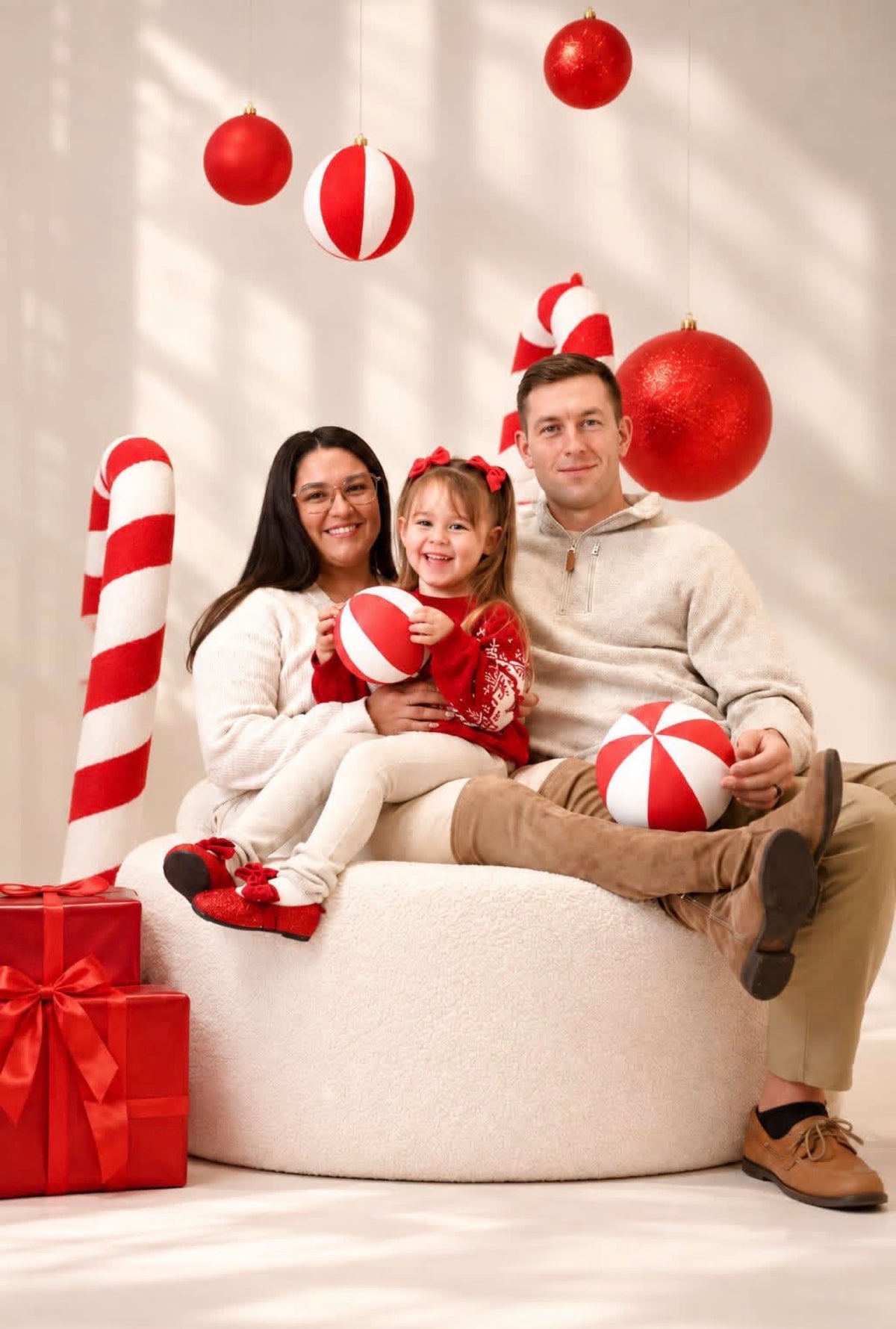 Giant red and white Christmas baubles and Candy Cane props used in a family holiday photography setup
