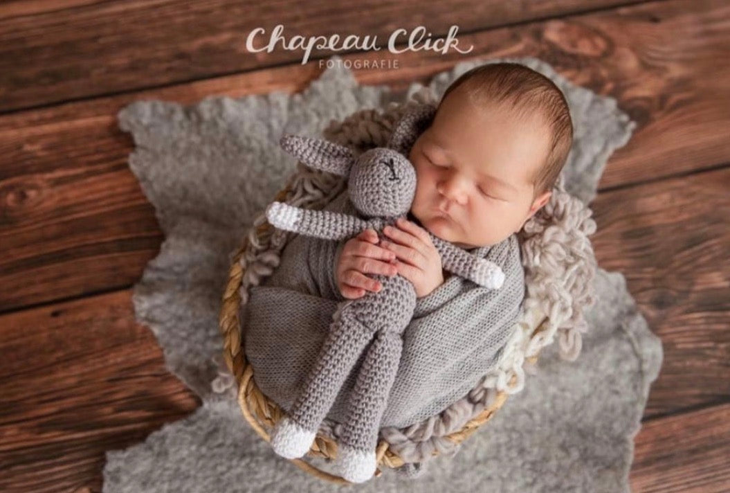 Grey hand-felted irregular wool blanket layered beneath a newborn in a photography basket