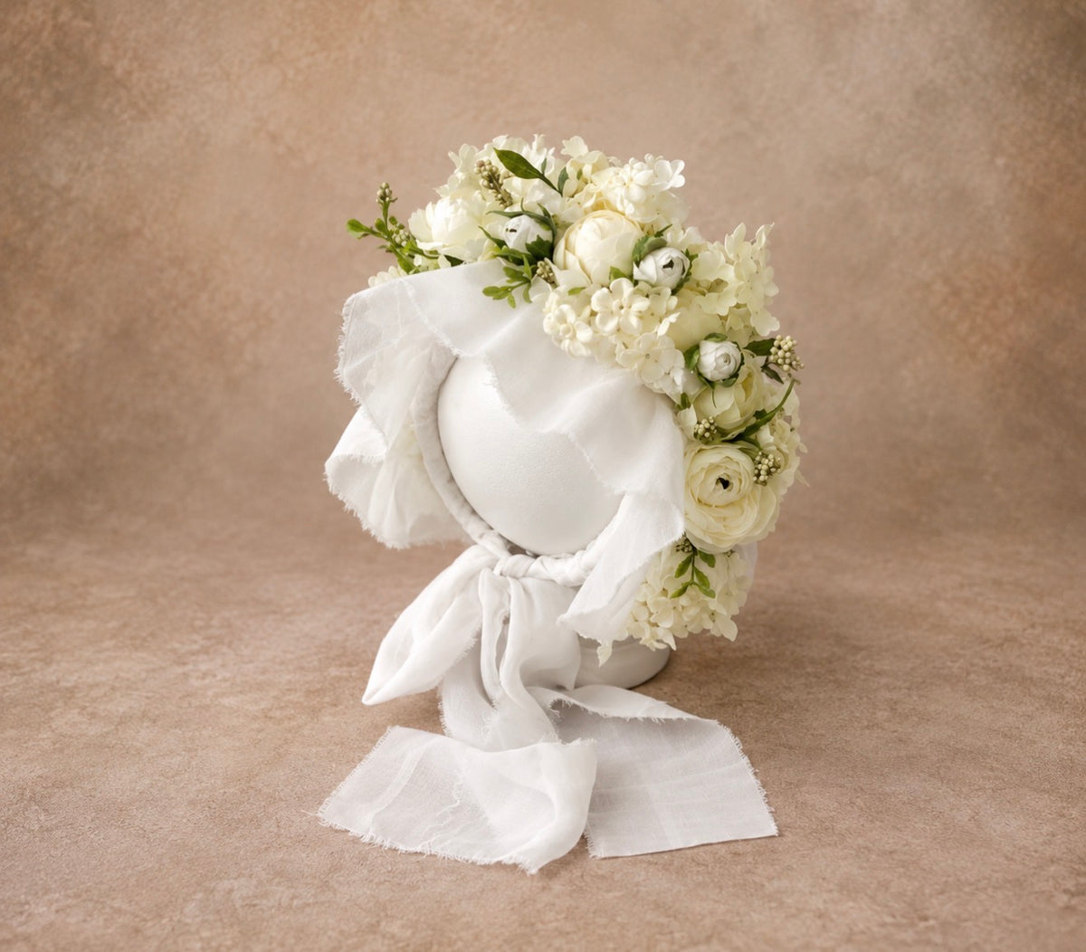 Side view of handmade ivory floral bonnet with white flowers and green botanical accents for fine art photography