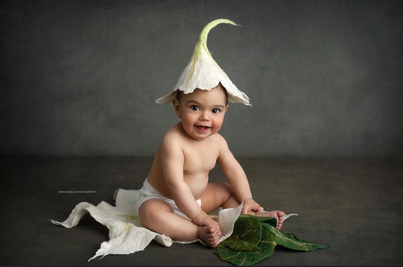 Sitter photography styling with ivory hand-felted lily flower bonnet and botanical leaf blanket