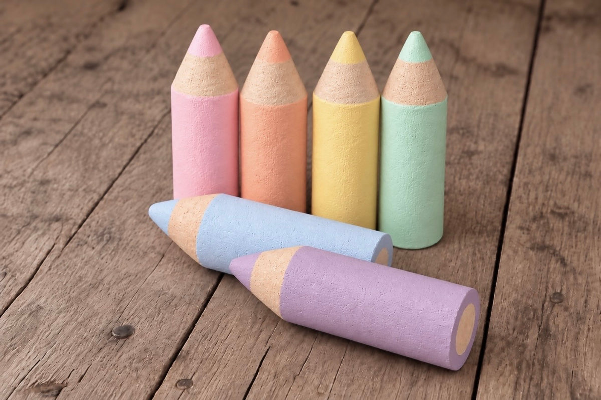 Six handmade mini Styrofoam coloured pencils in pink, peach, yellow, mint green, baby blue and lavender, arranged upright and horizontally on rustic wooden flooring