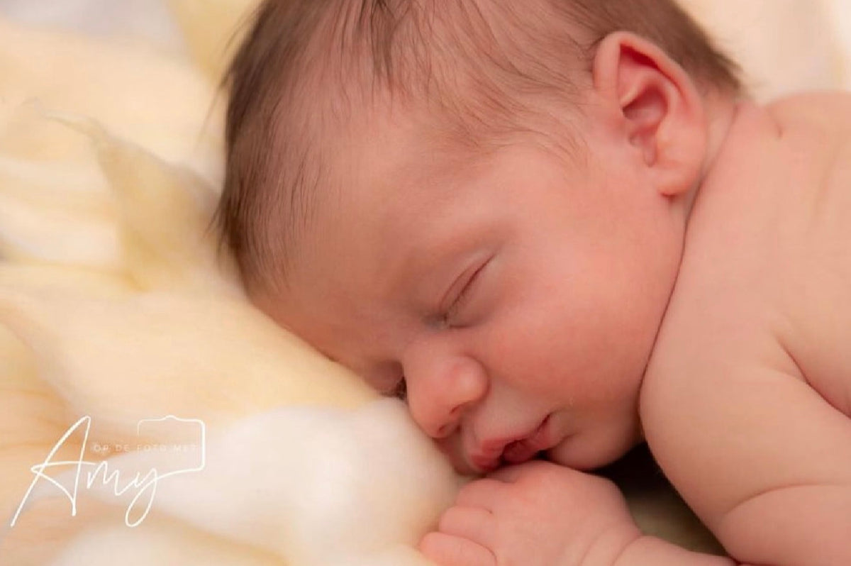 Close-up newborn portrait styled on a soft ivory felted wool petal photography blanket