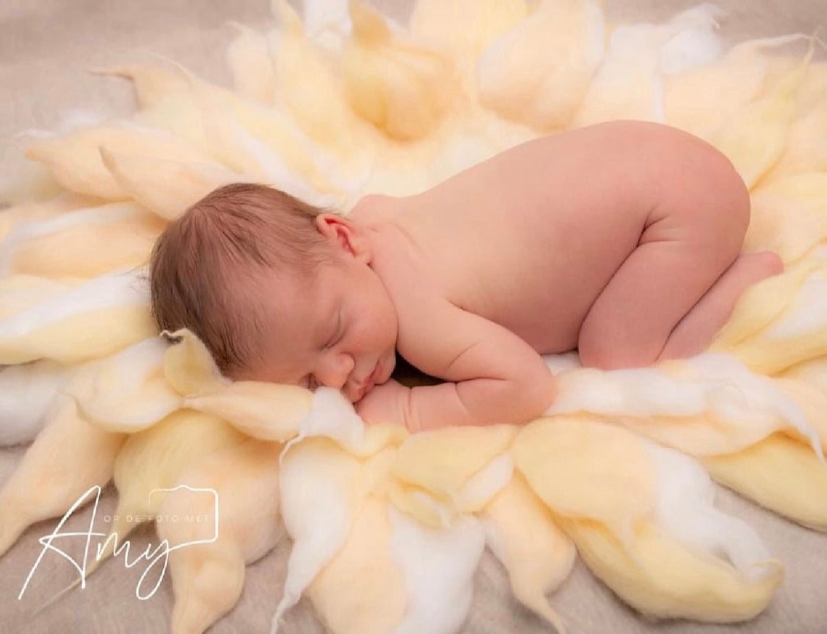 Newborn posed on a pure cloud and butter yellow hand-felted wool petal blanket for fine art baby photography