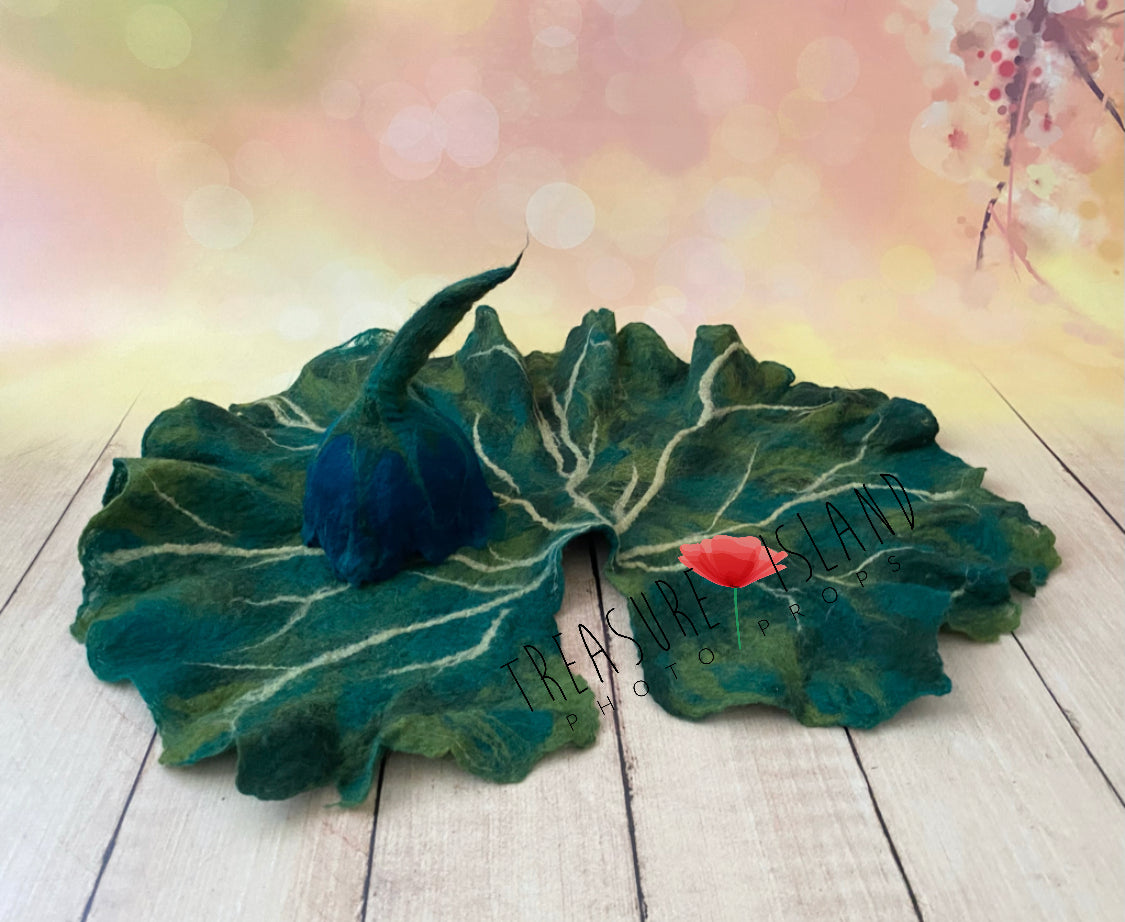 Noctulina handmade midnight blue and green felted bonnet displayed on botanical leaf for newborn photography