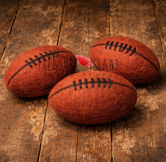 Three orange hand-felted rugby balls with dark lacing in different sizes for newborn and sitter photography