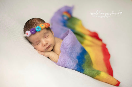 Newborn wrapped in a hand-felted classic rainbow wool wrap for photography
