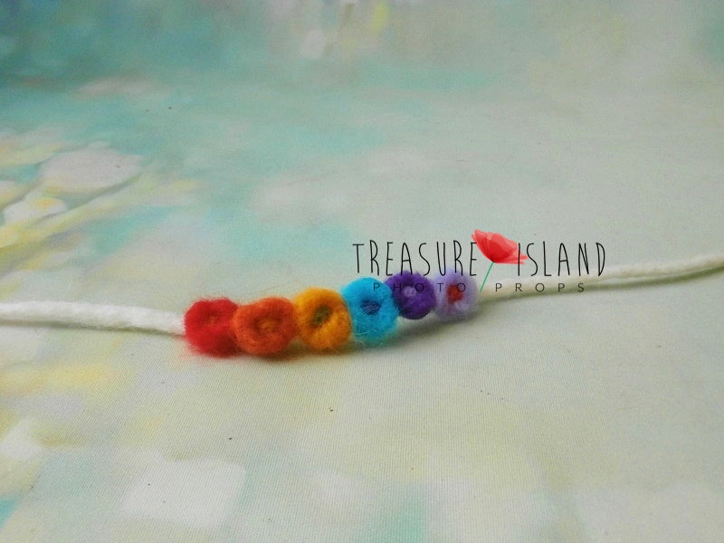 Hand-felted newborn tieback with miniature wool details in classic rainbow colors
