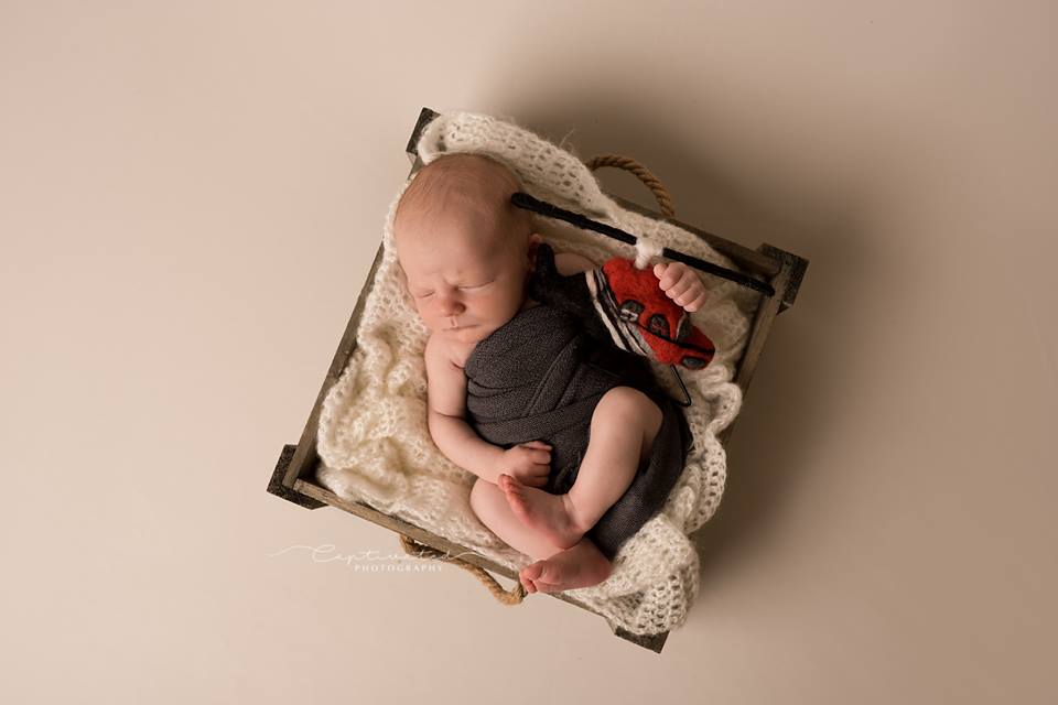 Newborn holding a hand-felted rescue helicopter during a themed photography session