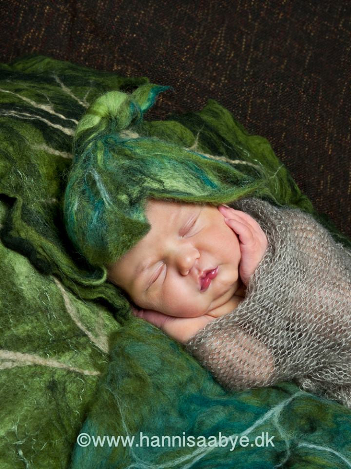 Newborn wearing a hand felted Forest Leaf Bonnet with sculptural green leaves