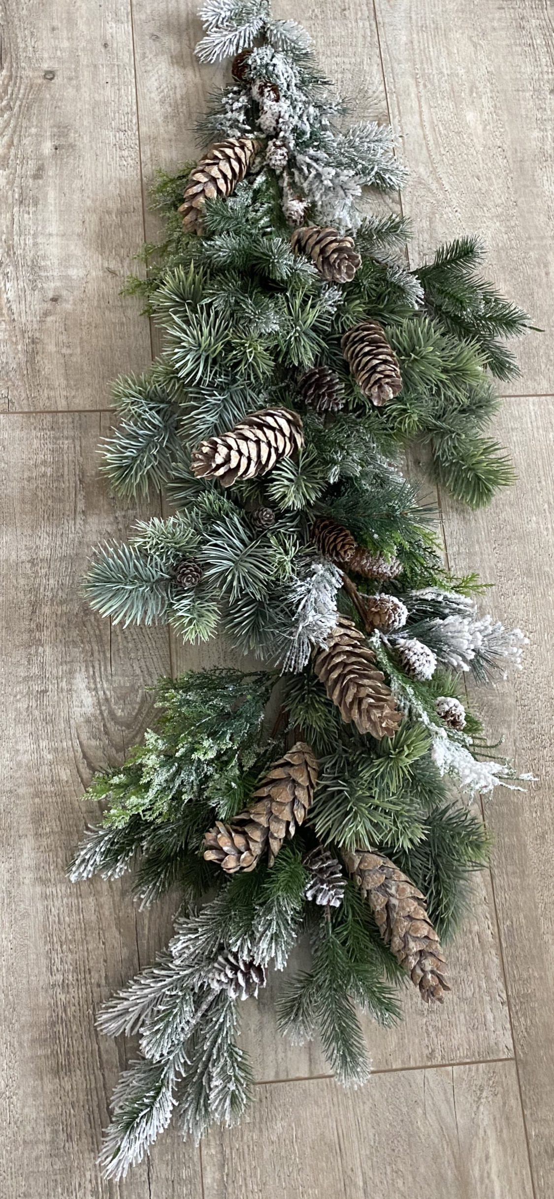 Frosted winter pine garland with snow-dusted evergreen branches and natural pinecones for Christmas photography