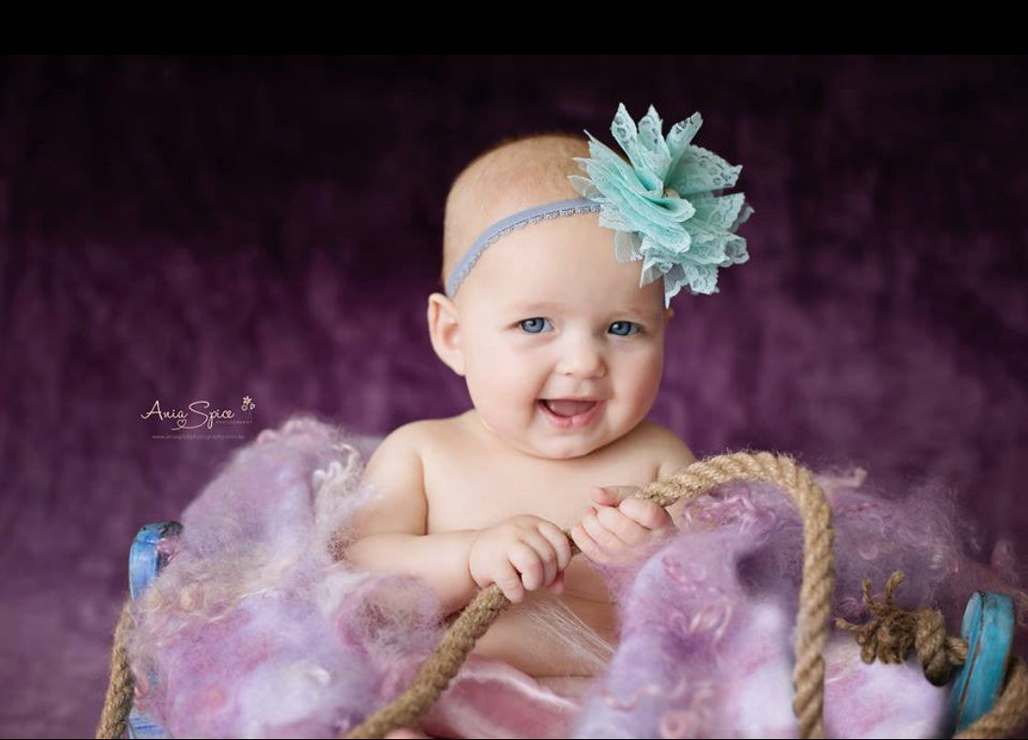 Smiling baby posed with a lilac and lavender curly wool photography blanket in a rustic wooden prop, photographed by Ania Spice Photography