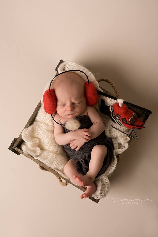 Newborn wearing felted pilot headphones with handmade rescue helicopter prop
