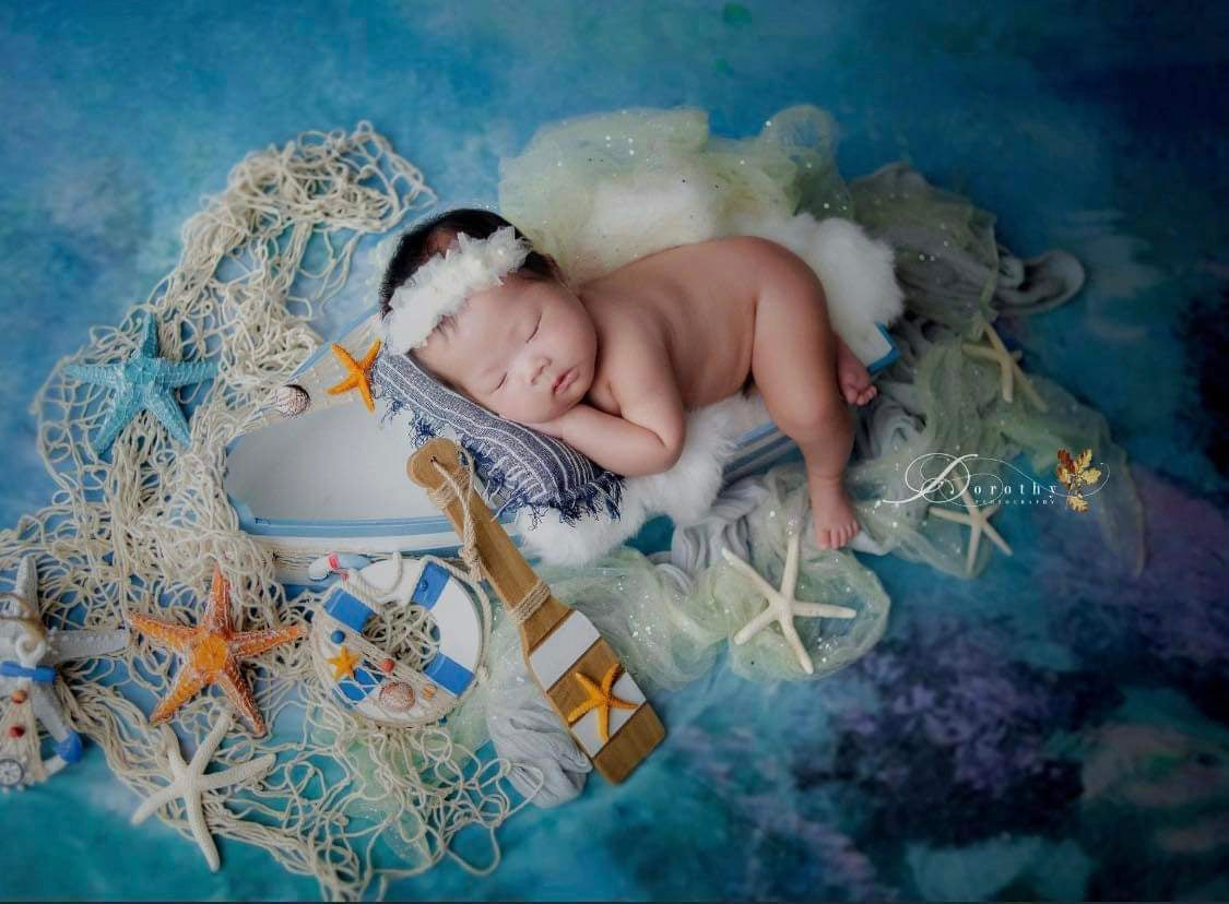 Newborn ocean photography setup styled with the blue and turquoise Ocean Wave felted blanket
