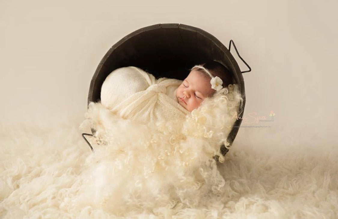 Pearl White curly wool blanket with natural sheep curls styled in a newborn bucket photography setup