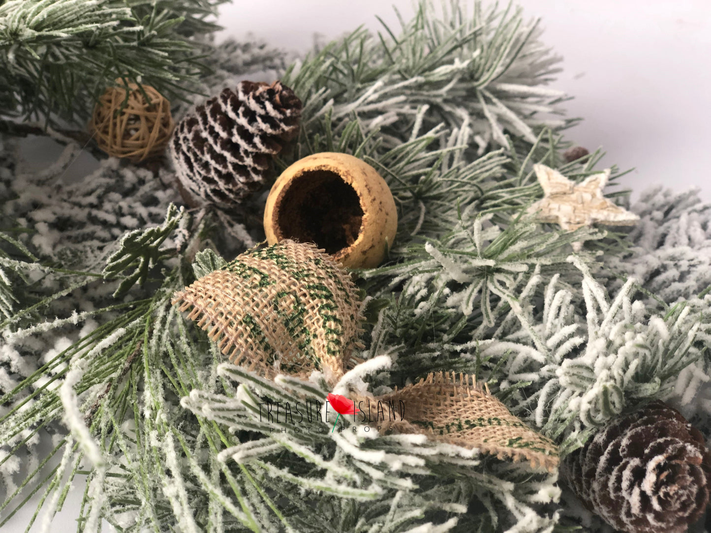 Close-up of snowy Christmas garland with pinecone, burlap bow and natural decorative accents