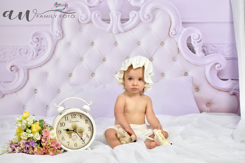 Baby wearing white bonnet and bloomers set for sitter and Cake Smash photography